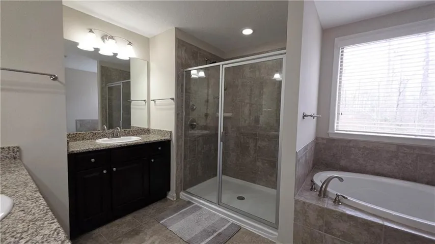 A spacious layout features a tiled walk-in shower alongside a soaking tub.