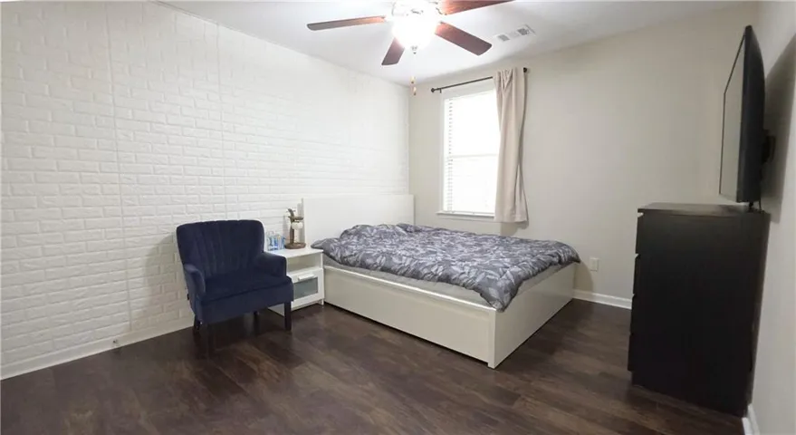 Rich hardwood flooring anchors this cozy bedroom, complete with a textured white feature wall.