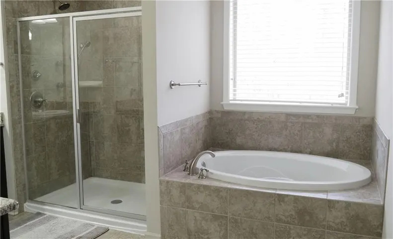 An inviting soaking tub pairs beautifully with a glass-enclosed walk-in shower.