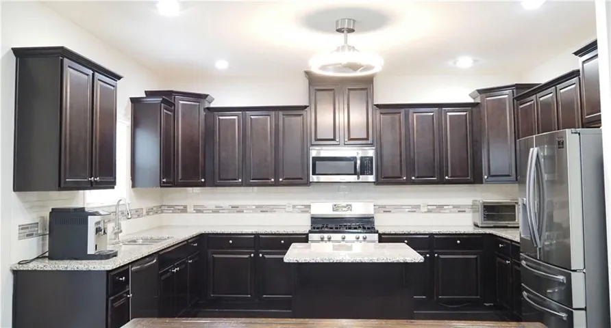 Rich dark cabinetry pairs beautifully with granite countertops and modern stainless steel appliances.