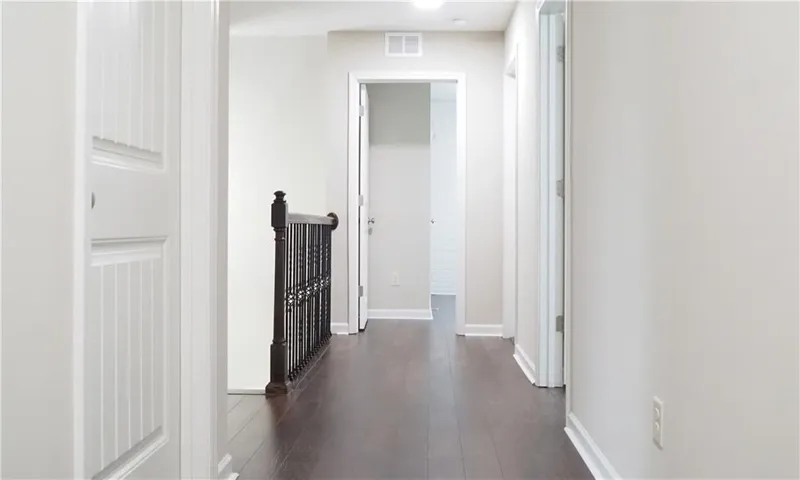 Rich dark wood flooring and clean white trim anchor this upper-level hallway space.
