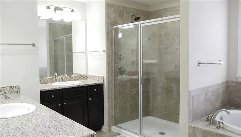 A classic bath installation showcases granite counters alongside a glass shower and deep tub.