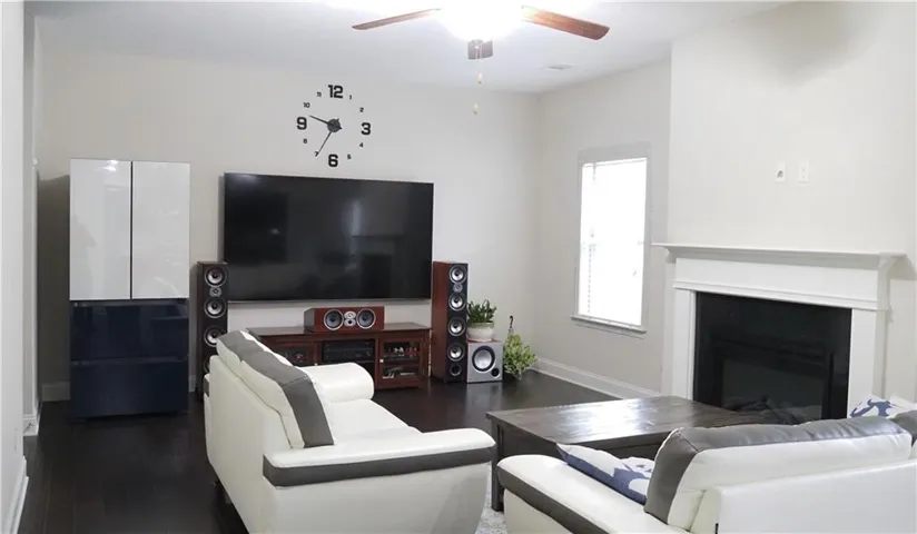 A classic fireplace with a white mantel anchors this comfortable living space featuring dark wood floors.
