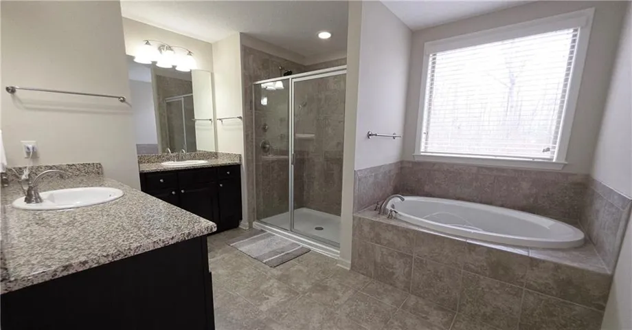 Stone counters, a glass shower, and a built-in tub define this main bathroom.
