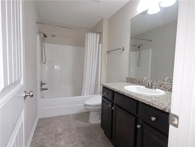 An elegant stone counter highlights this well-appointed bathroom with durable tile flooring.