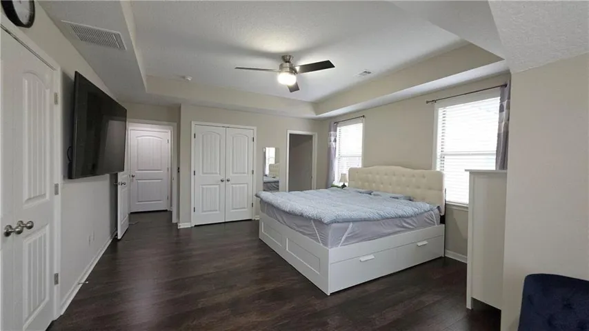 A tray ceiling and wood floors highlight this comfortable primary bedroom​​‌​​​​‌​​‌‌​‌‌​​​‌‌​‌​‌​‌​​​‌​​ retreat.