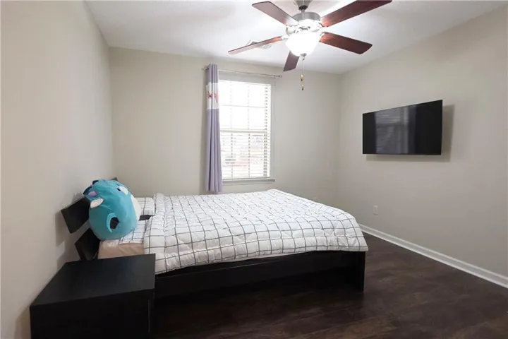 Rich dark wood flooring anchors this comfortable bedroom featuring a classic double-hung window.