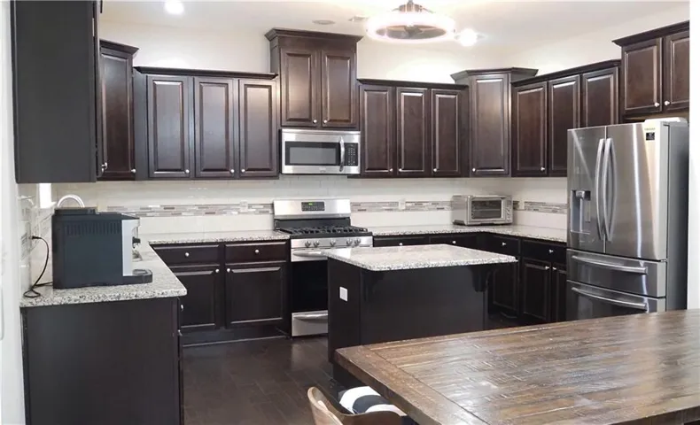 Rich dark wood cabinetry pairs beautifully with sleek granite countertops in this modern culinary workspace.