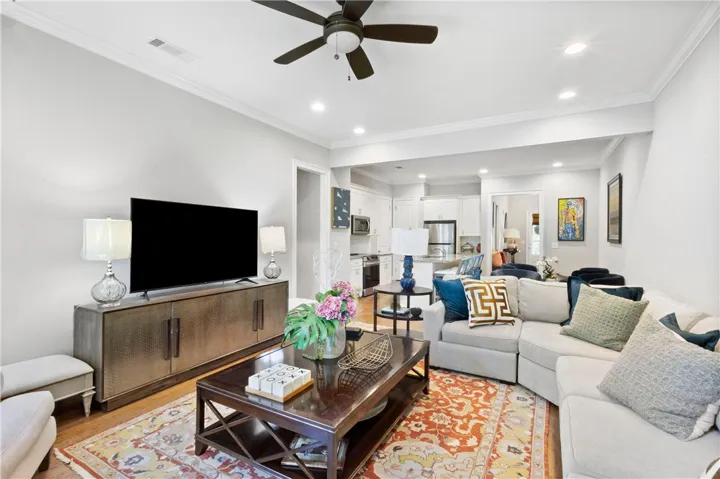 Hardwood floors and crisp crown molding frame this welcoming living room opening to the kitchen.