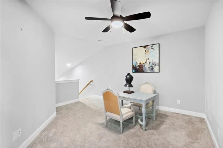 An open loft space upstairs features neutral carpeting, clean lines, and a vaulted ceiling.