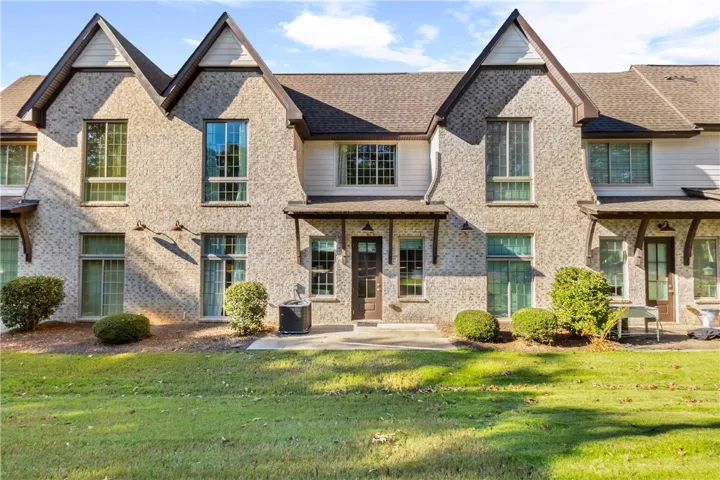 A classic brick exterior features tall windows and gabled rooflines along a grassy lawn.
