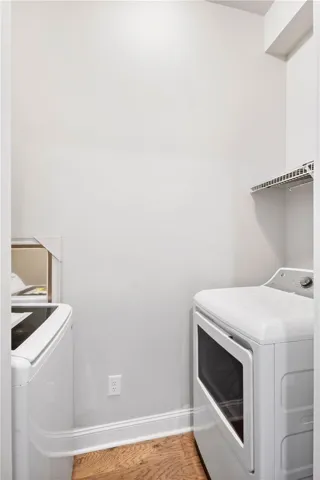 A dedicated laundry space displays warm wood flooring under a high ceiling.
