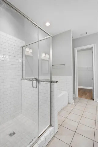 Crisp subway tile frames a glass shower and adjacent soaking tub.