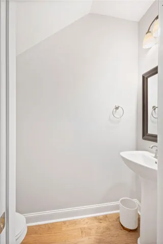 Warm hardwood floors complement the clean lines of this under-stairs powder room.