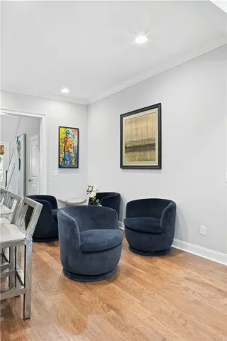 Rich hardwood floors and classic crown molding elevate this welcoming sitting area.