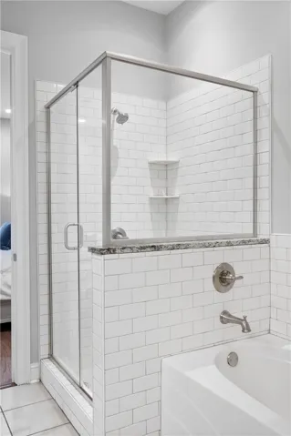 White subway tile lines the walk-in glass shower next to a built-in bathtub.