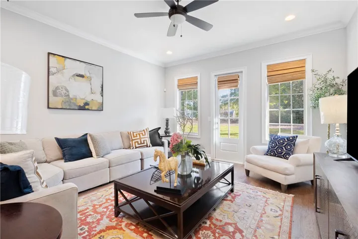Rich wood-look flooring and crown molding frame a welcoming space filled with natural light.