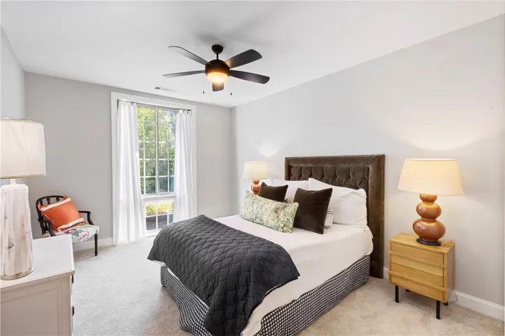 Plush carpeting and a large window facing the yard anchor this peaceful bedroom design.