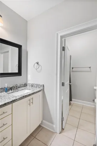 A classic bathroom layout features granite counters, structured cabinetry, and neutral tile flooring.