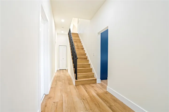 Warm wood flooring and clean lines define this inviting modern entryway with a central staircase.