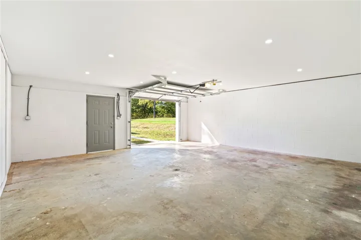 A spacious garage features concrete floors, recessed lighting, and access to the outdoor yard.