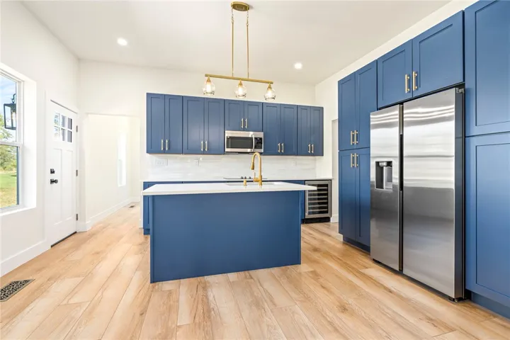 Richly toned cabinetry joins clean surfaces and warm flooring in this well-appointed culinary space.