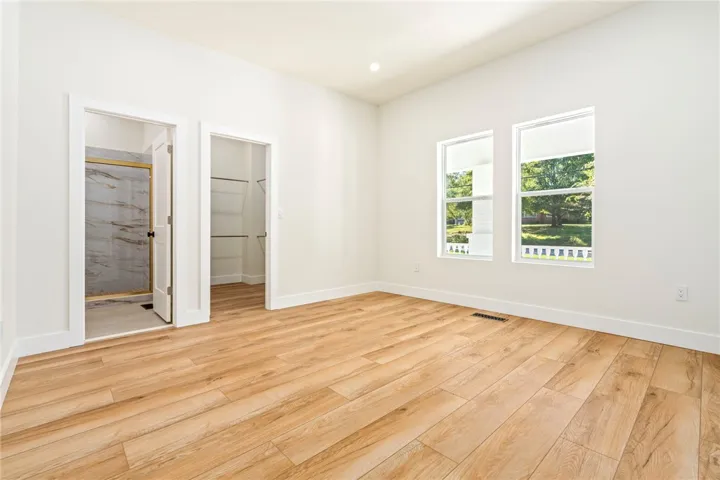 Gleaming wood-look floors and neutral walls anchor this clean, airy bedroom space.
