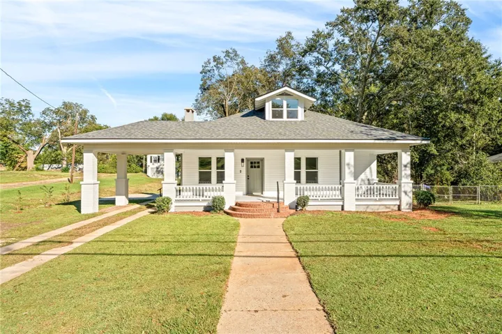 A classic craftsman-style porch and matching carport define the welcoming facade of this charming home.