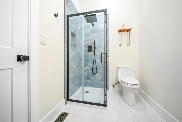 Sleek contemporary tile floors anchor this modern bathroom featuring a glass-enclosed walk-in shower.