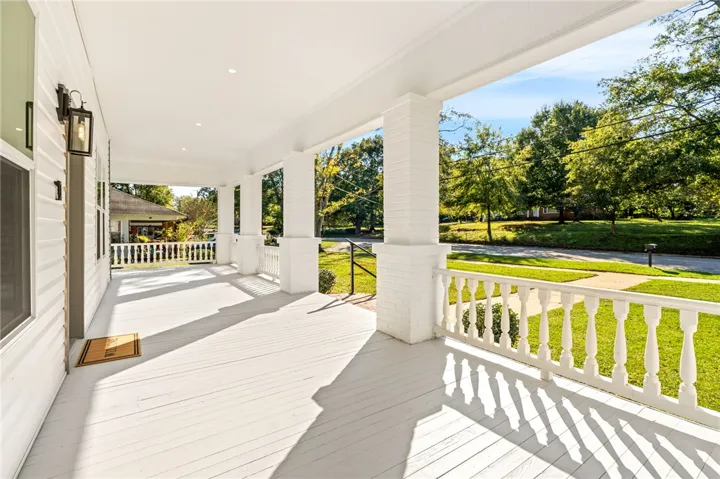 An inviting covered front porch with clean columns overlooks the surrounding neighborhood greenery.