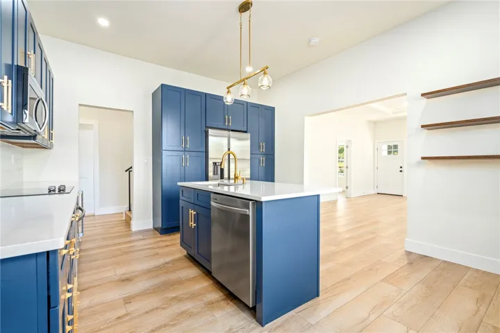 A spacious kitchen features vibrant cabinetry, a central island, and seamless wood flooring.
