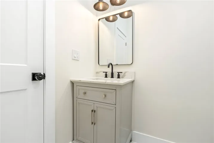 An elegant powder room features a classic single vanity topped with clean stone counters.
