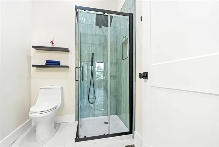 Clean lines and geometric floor tiling frame a modern glass-enclosed walk-in shower.