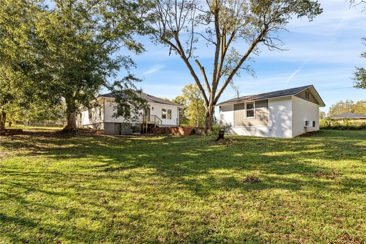 Mature trees shade a spacious green lawn leading up to the main house and outbuilding.