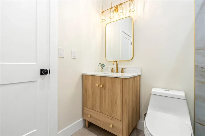 Elegant gold hardware pairs beautifully with a modern light-toned wood vanity and sleek stone countertop.