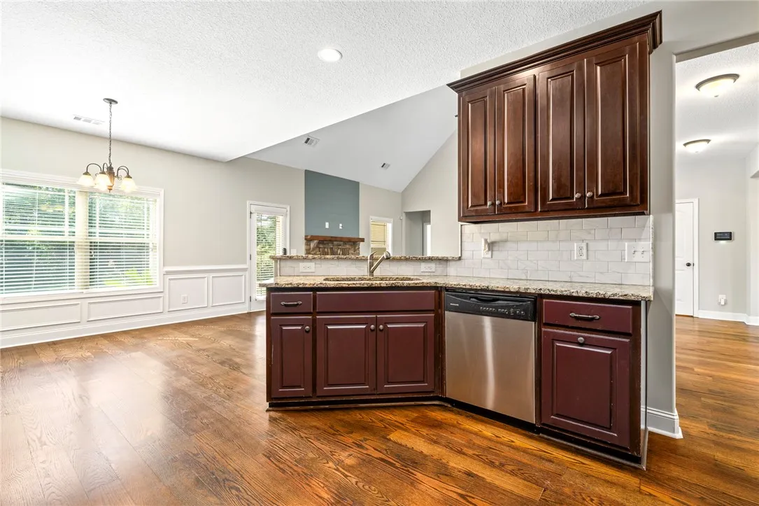 Rich hardwood flooring complements deep wood cabinetry and stone countertops in this airy kitchen.