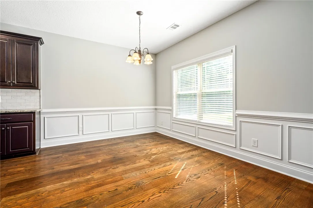 Rich hardwood floors complement elegant wainscoting and classic crown molding in this refined dining area.