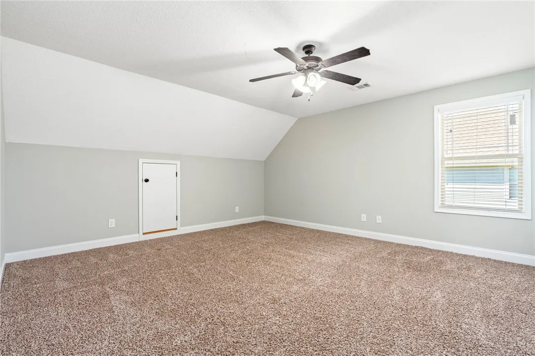 A spacious upper-level bedroom features plush carpeting, sloped ceilings, and access to attic storage.