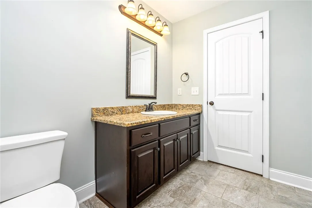 Richly patterned stone counters top the dark wood vanity in this well-appointed washroom.