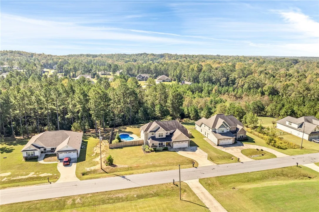 An aerial perspective showcases an established neighborhood bordered by dense, mature woodlands.