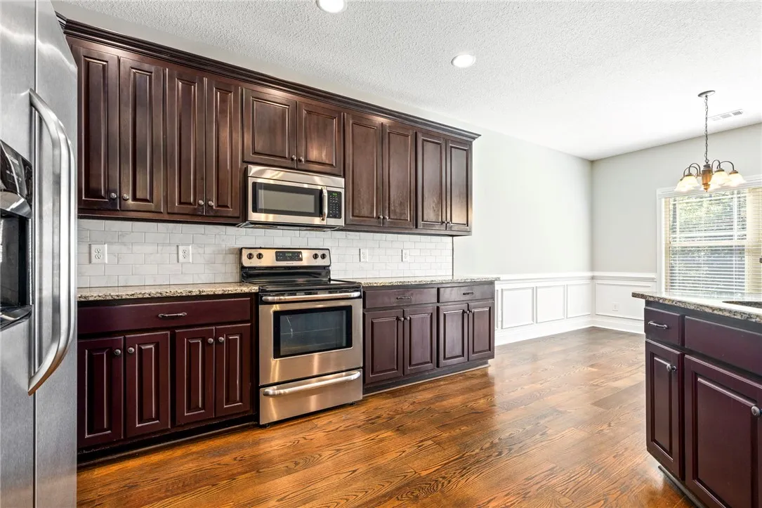 Rich wood cabinetry and classic wainscoting frame a bright culinary workspace with polished hardwood floors.