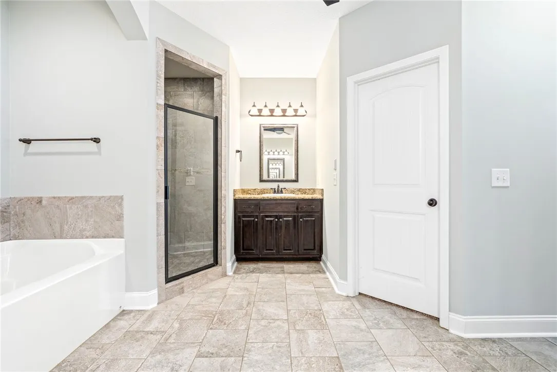 Fine tile flooring pairs with a glass-enclosed shower and adjacent soaking tub.
