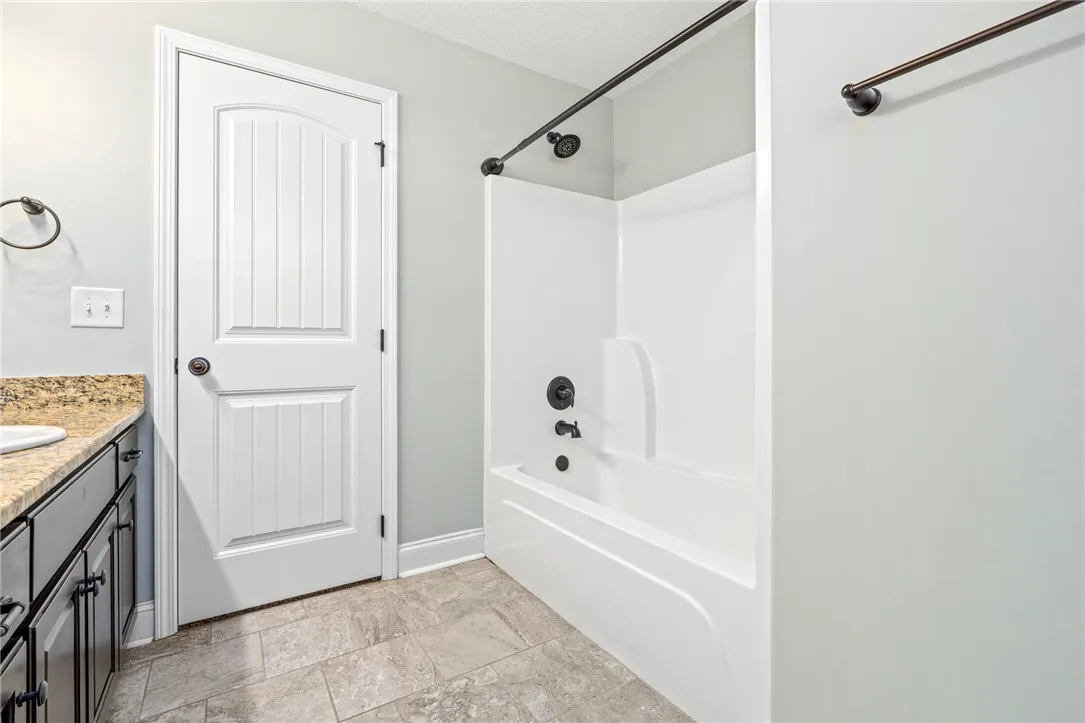 Tiled flooring and granite countertops complement the clean alcove tub installation in this bathroom.