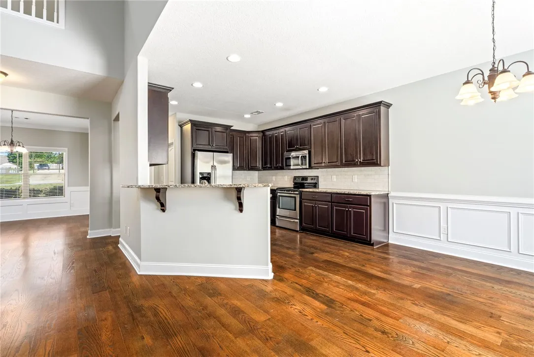 Rich hardwood flooring complements dark cabinetry and stone countertops in an open layout.