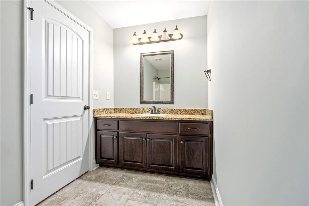 Rich wood cabinetry and natural stone countertops anchor this serene bathroom space.