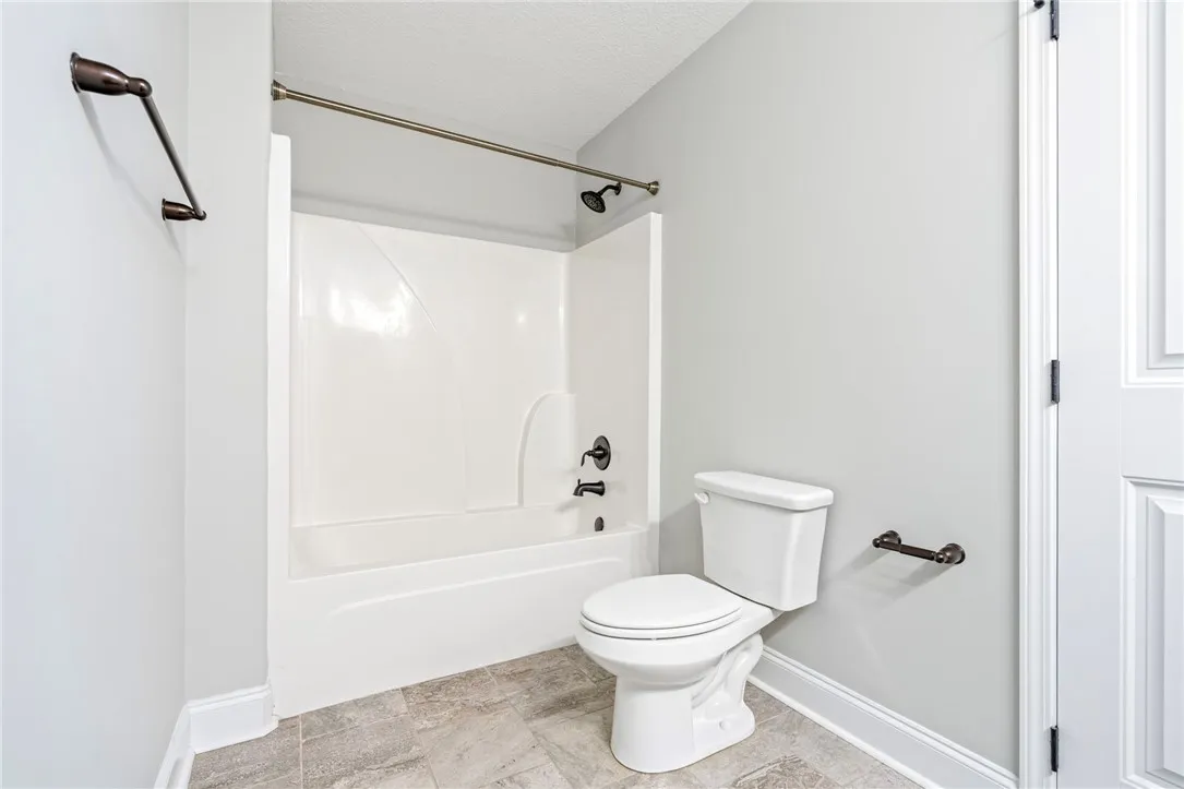 Textured tile flooring and oil-rubbed bronze fixtures complete this clean bathroom layout.