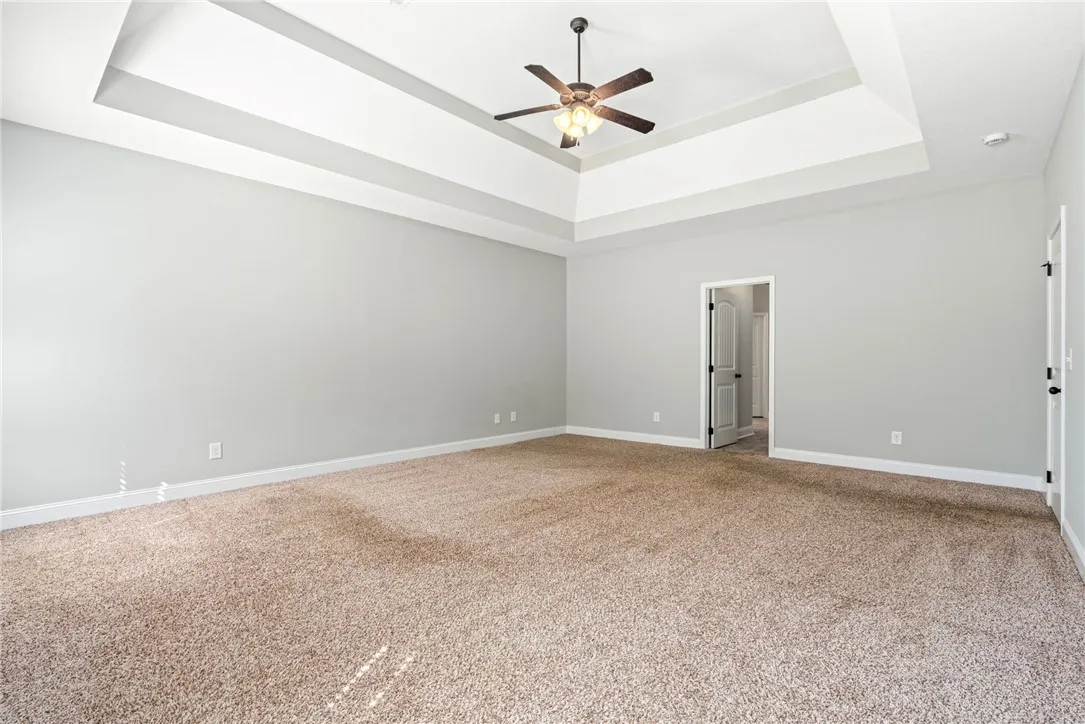 An elegant tray ceiling anchors this spacious bedroom complete with neutral carpeting.