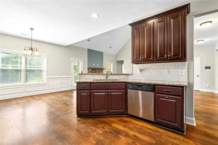 Rich hardwood flooring complements deep wood cabinetry and stone countertops in this airy kitchen.