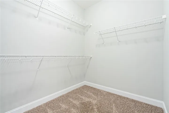 Multi-tier wire shelving maximizes storage potential in this carpeted walk-in closet.