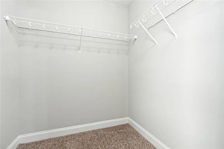 Ample wire shelving lines this functional closet space completed by soft carpet underfoot.